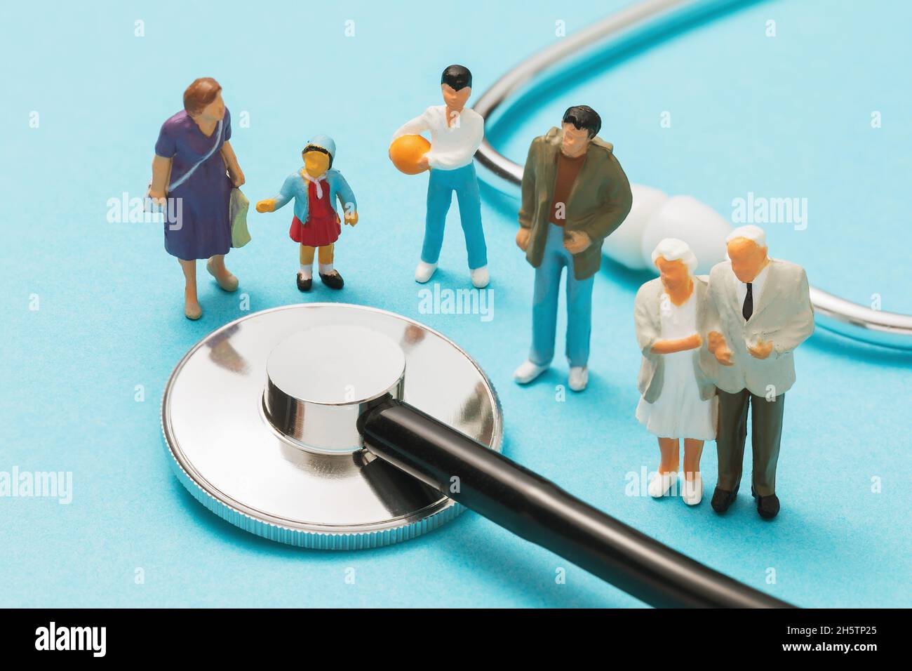 Figure giocattolo di plastica della gente e uno statoscopio medico su uno sfondo blu, concetto di medico di famiglia Foto Stock
