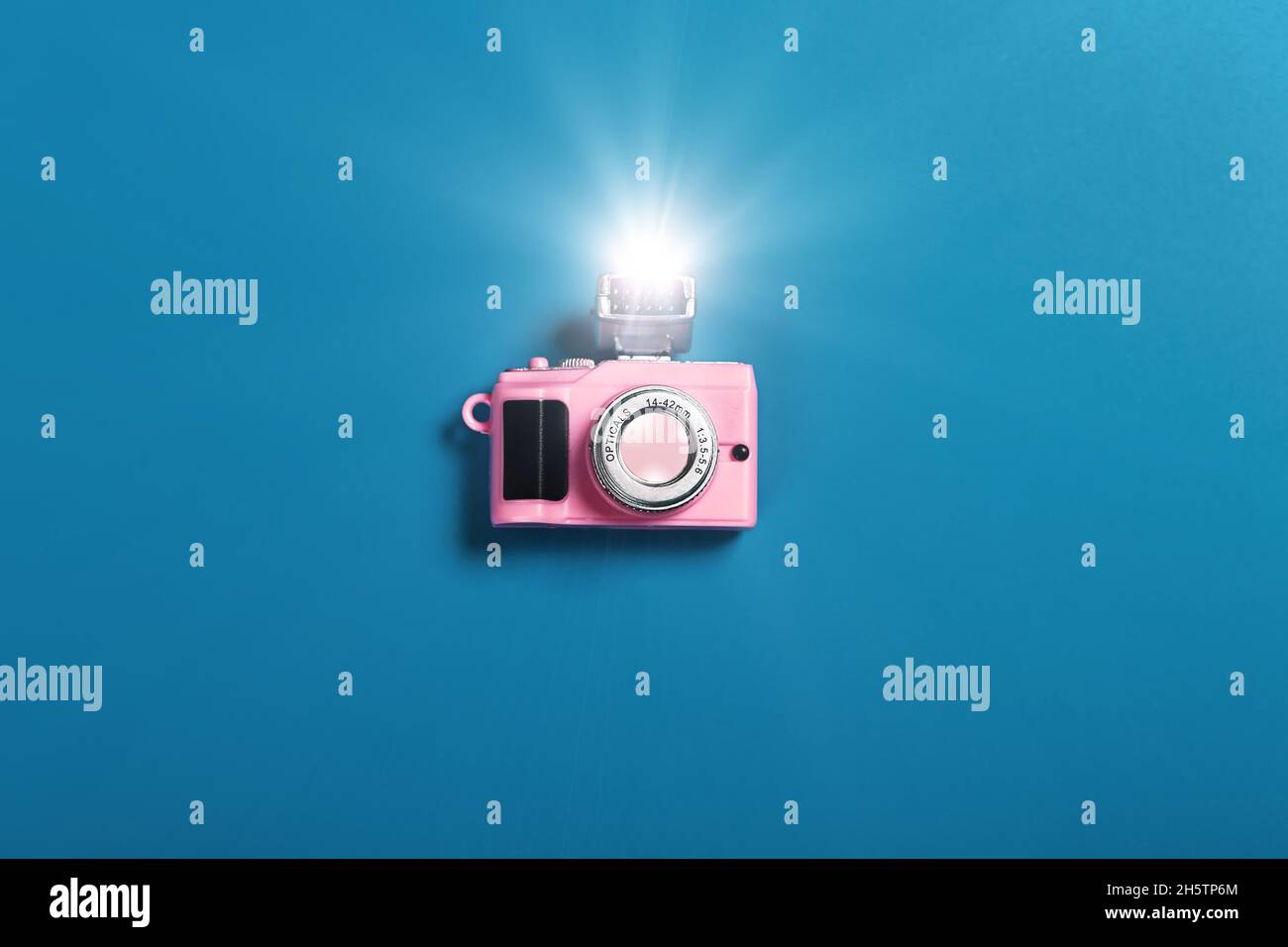 piccola fotocamera rosa con flash su sfondo blu Foto Stock