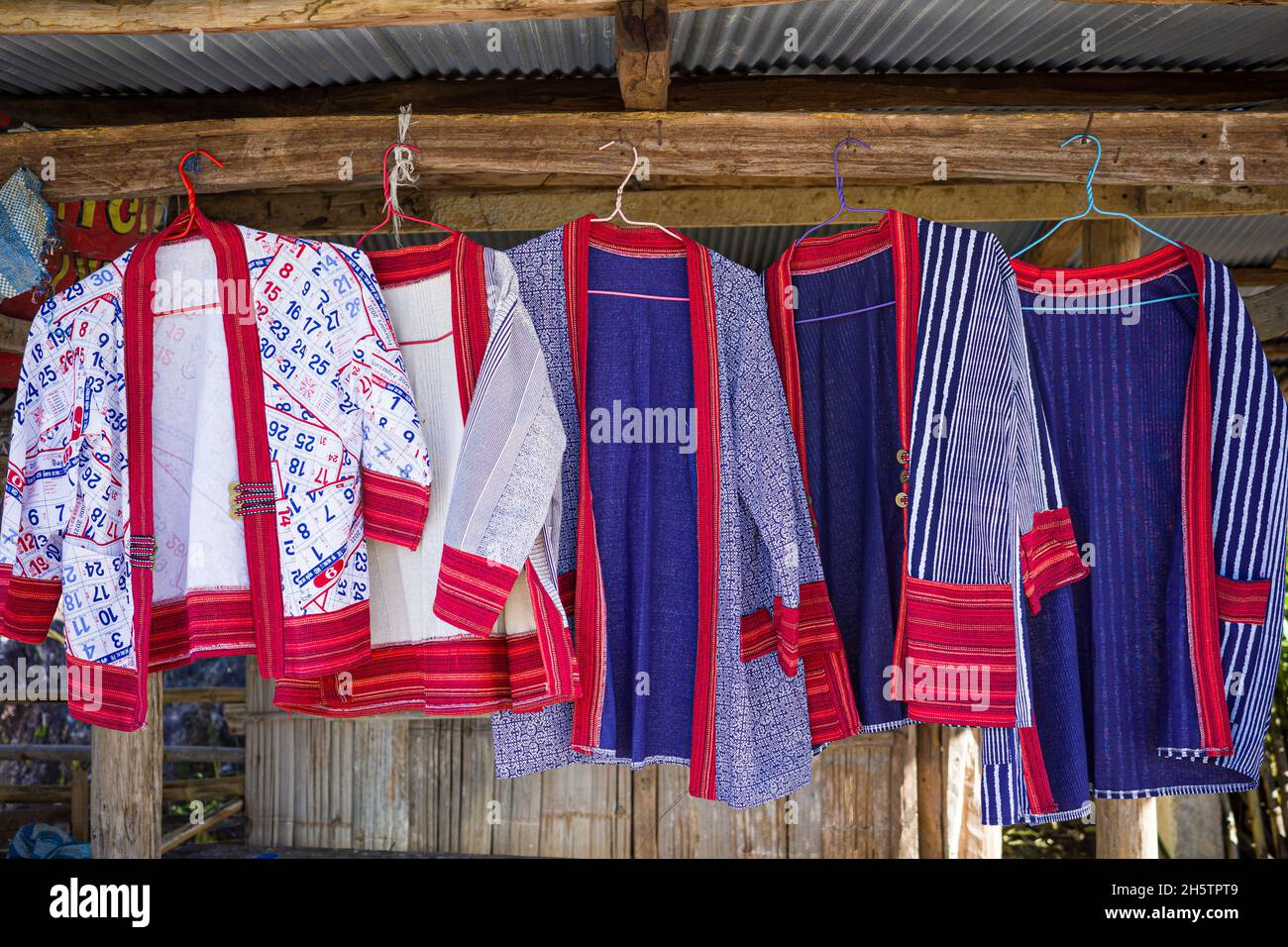 Colorate magliette alpinistiche in blu e rosso appese su una rastrelliera in legno di negozio di abbigliamento rurale. Foto Stock