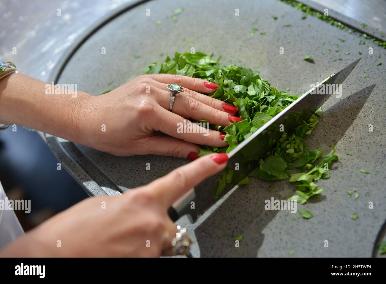 Primo piano di una donna le mani tagliando l'erba con un coltello in cucina Foto Stock