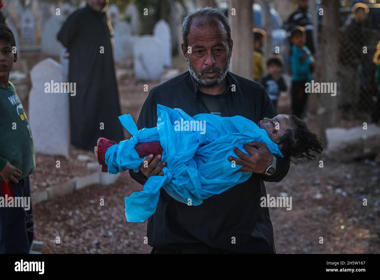 Broma, Siria. 11 Nov 2021. Un parente trasporta il corpo della bambina di 1 anno Marwa Khader, una delle vittime di un bombardamento aereo, effettuato da aerei da guerra russi sul villaggio di Broma nel Governatorato di Idlib. Almeno cinque civili, di cui tre bambini, sono stati uccisi giovedì in attacchi aerei russi su una roccaforte dei ribelli in Siria, un gruppo di monitoraggio ha riferito. Credit: ANAS Alkharboutli/dpa/Alamy Live News Foto Stock