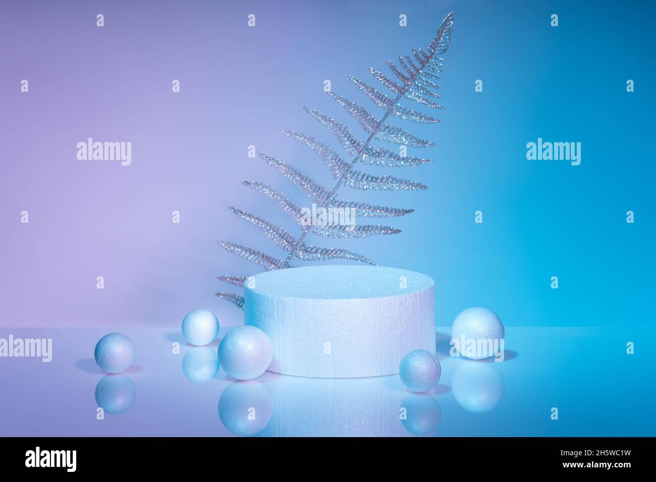 Podio cilindrico bianco su sfondo blu-rosa con decorazioni natalizie. Piattaforma minimalistica festiva, concetto di vendita e vetrine per presen Foto Stock