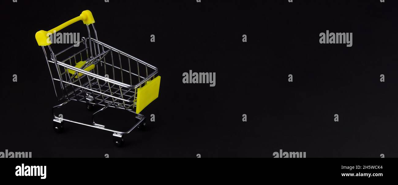 Carrello acquisti su sfondo nero con spazio vuoto per l'inserimento del testo. Concetto aziendale. Foto Stock