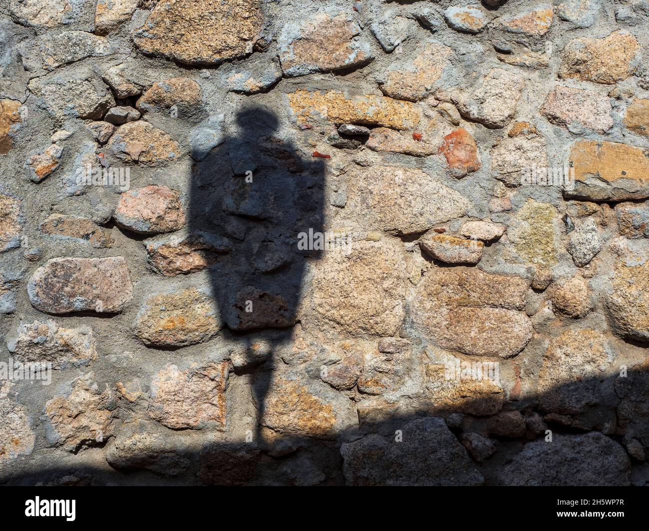 Ombra di una lampada stradale su un muro di pietra del castello di Trujillo. Foto Stock