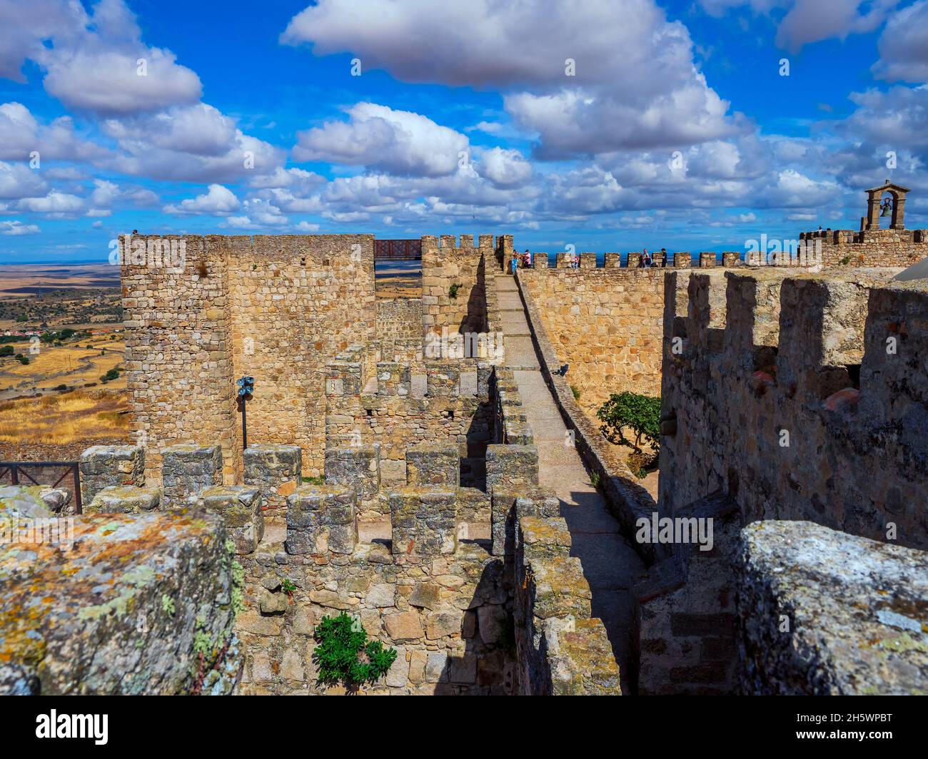 Mura e merlamenti del castello medievale di Trujillo in una giornata di cielo blu con le nuvole. Foto Stock