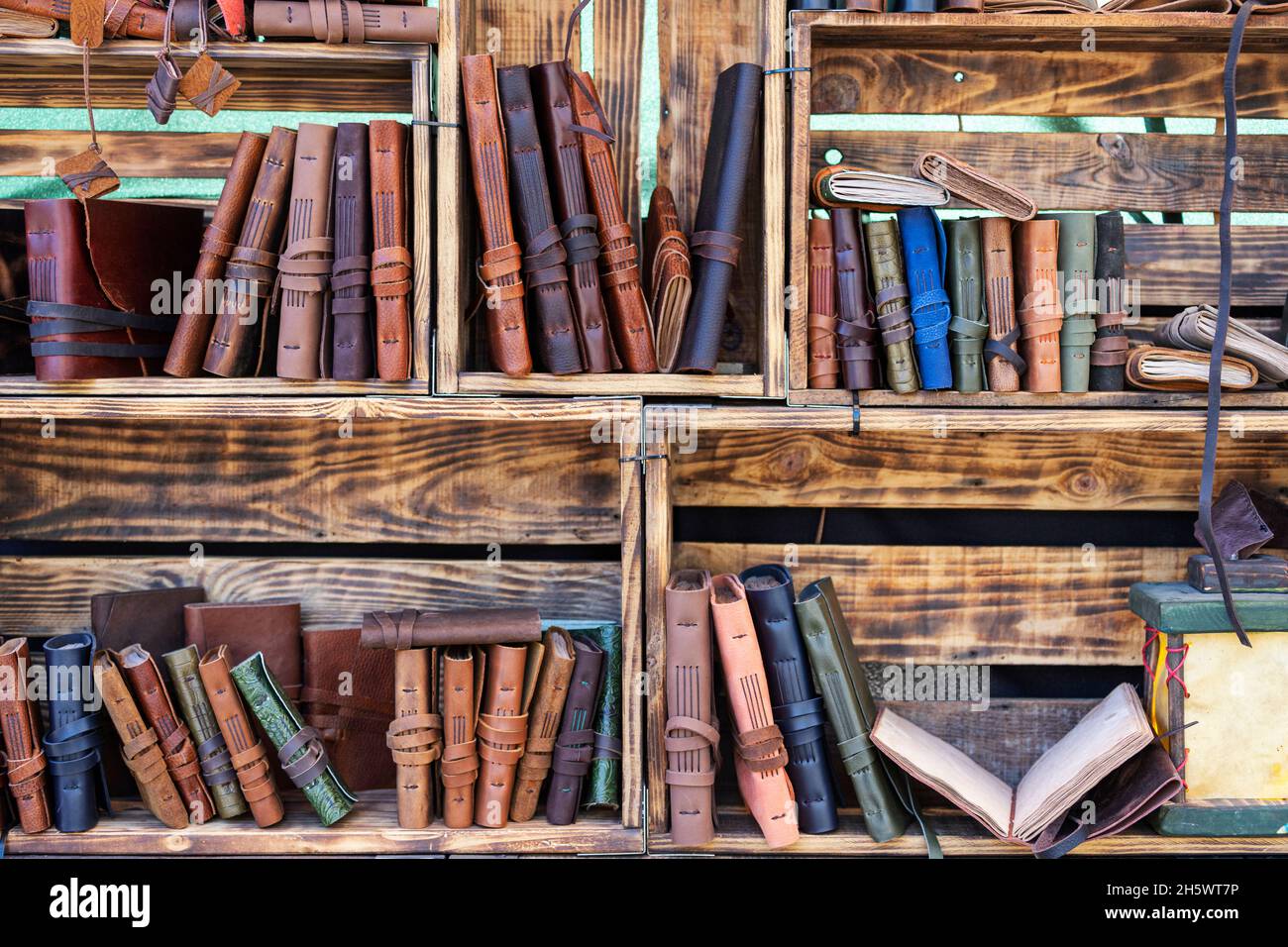 vista orizzontale di taccuini fatti a mano con rivestimento in pelle su scaffali da libro realizzati con scatole in legno. pelletteria con materiali riciclati Foto Stock