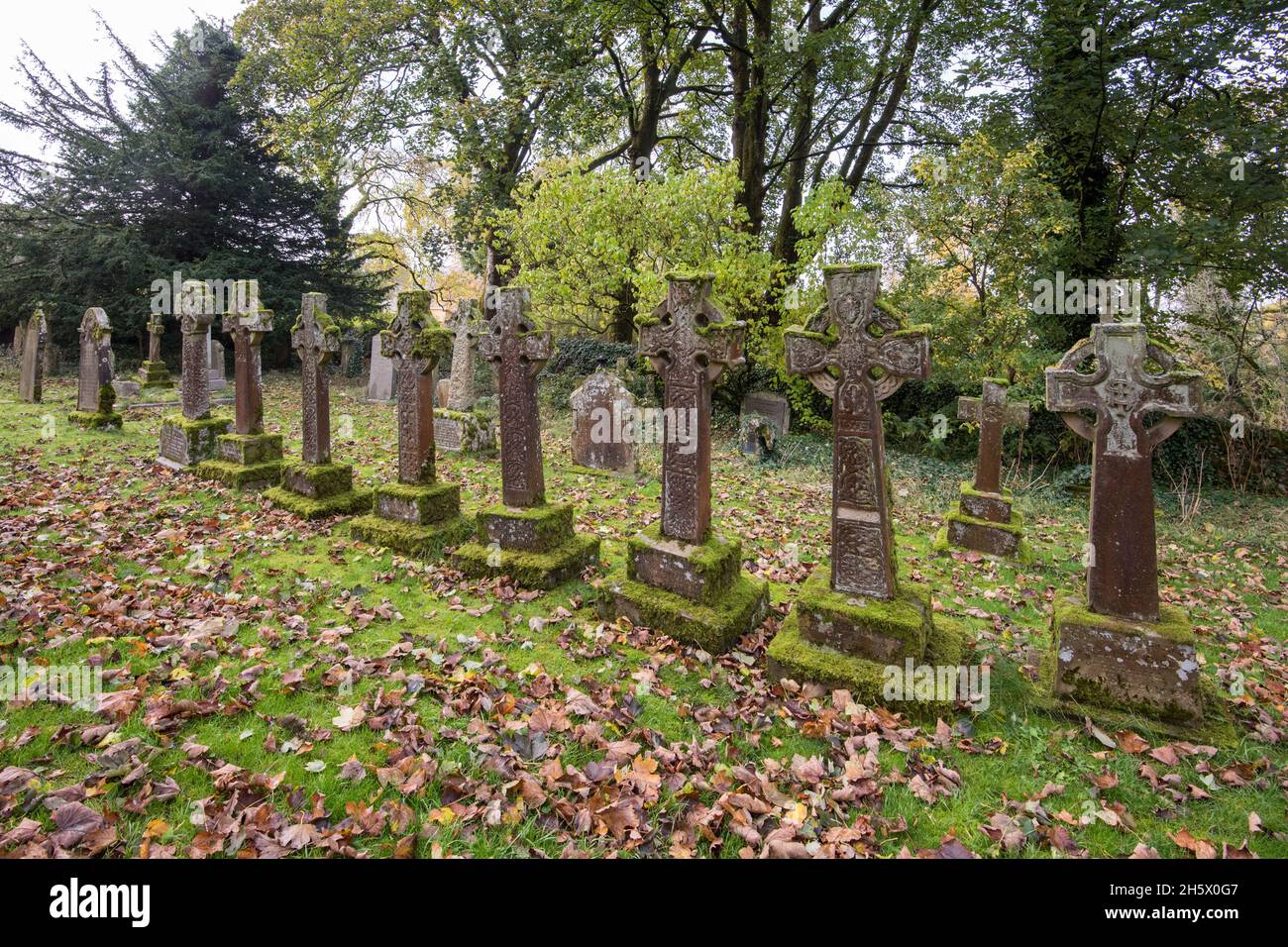 Interessante linea di lapidi a croce celtica ricoperta di muschio presso la chiesa di San Oswald di Arncliffe. Foto Stock