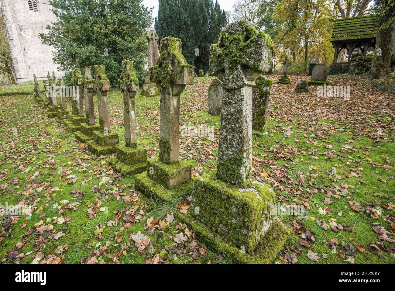 Interessante linea di lapidi a croce celtica ricoperta di muschio presso la chiesa di San Oswald di Arncliffe. Foto Stock