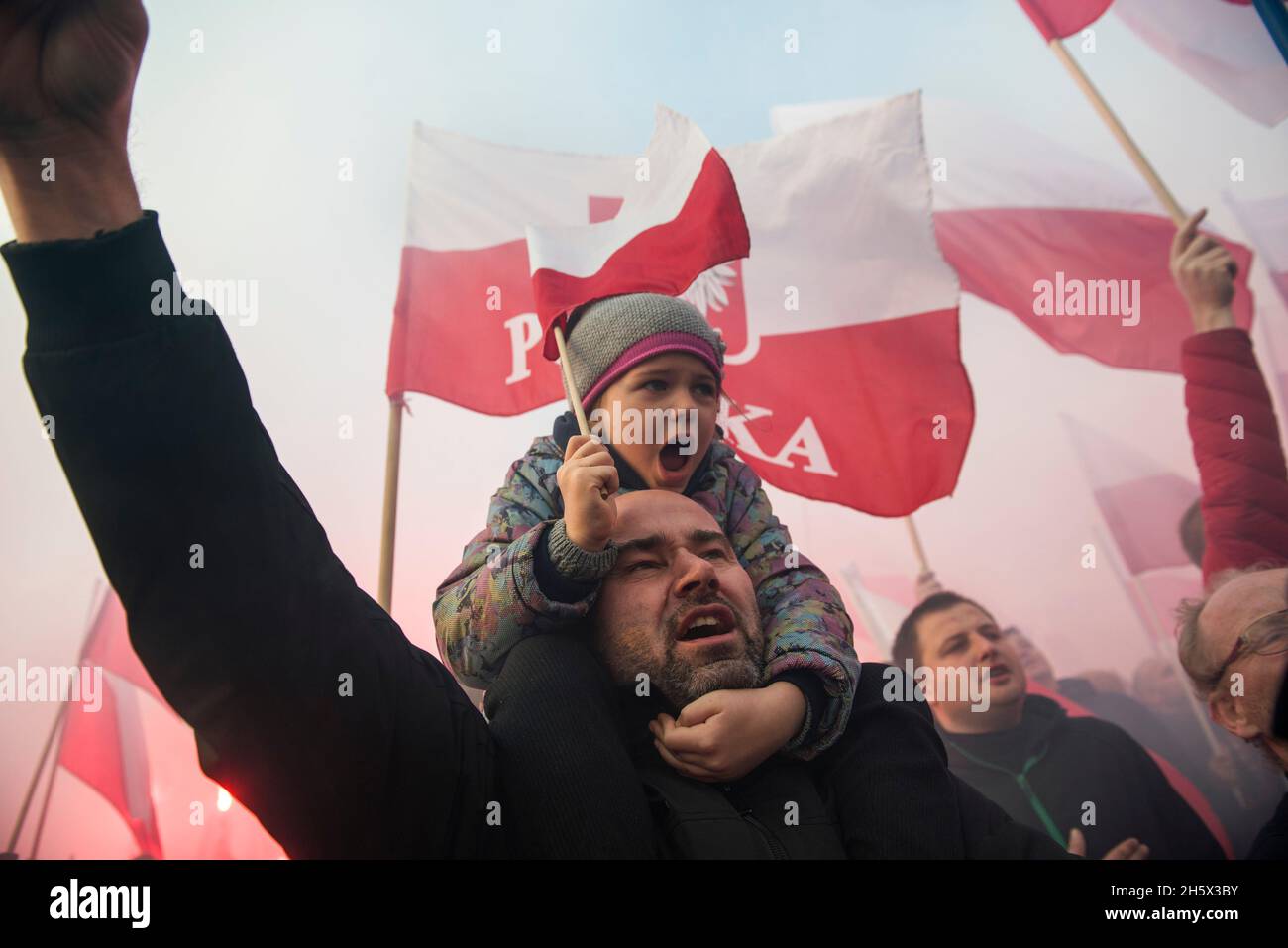 Varsavia, Polonia. 11 Nov 2021. Un uomo con sua figlia sulle spalle cantano slogan durante l'Indipendenza March.Poland National Independence Day segna l'anniversario dell'indipendenza del paese nel 1918. Il 11 novembre di ogni anno viene festeggiata a livello nazionale. Anche quest'anno decine di migliaia di polacchi hanno partecipato alla marcia della Giornata dell'Indipendenza a Varsavia organizzata da organizzazioni di estrema destra per celebrare il 103° anniversario della rinascita della Polonia come Stato indipendente. Lo slogan della marcia era: "L'indipendenza non è in vendita!". (Foto di Attila Husejnow/SOPA Images/Sipa USA) Foto Stock