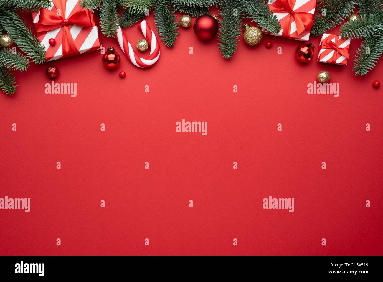 Sfondo rosso di Natale con ornamenti in abete e regali di vacanza. Disposizione piatta, vista dall'alto e spazio di copia per il testo Foto Stock