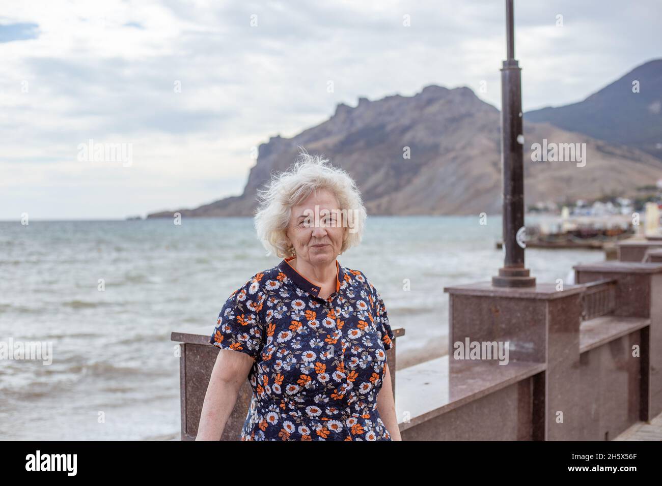 Ritratto di una donna anziana dai capelli grigi sul lungofiume del mare. Tempo libero e passatempo in pensione. Foto Stock