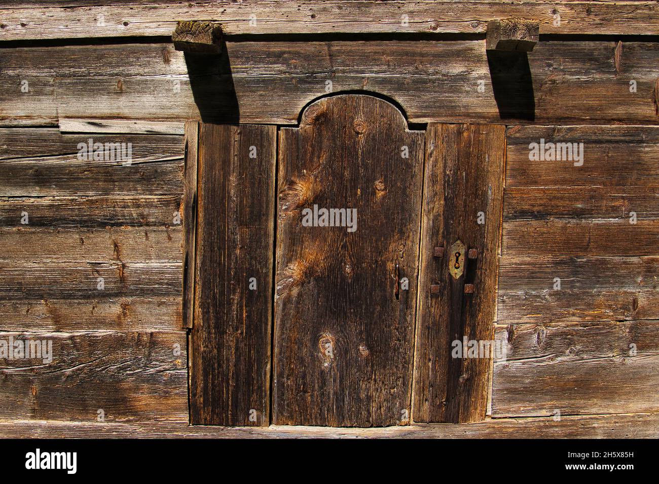 Vecchia porta in legno intemperie in un fienile tradizionale delle Alpi francesi, di almeno 200 anni. Foto Stock