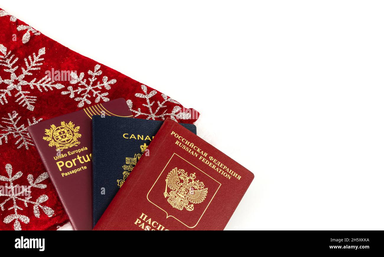 Tre diversi passaporti isolati su bianco con decorazioni natalizie. Passaporti canadesi, portoghesi e russi per l'ingresso in diversi paesi. Cl Foto Stock