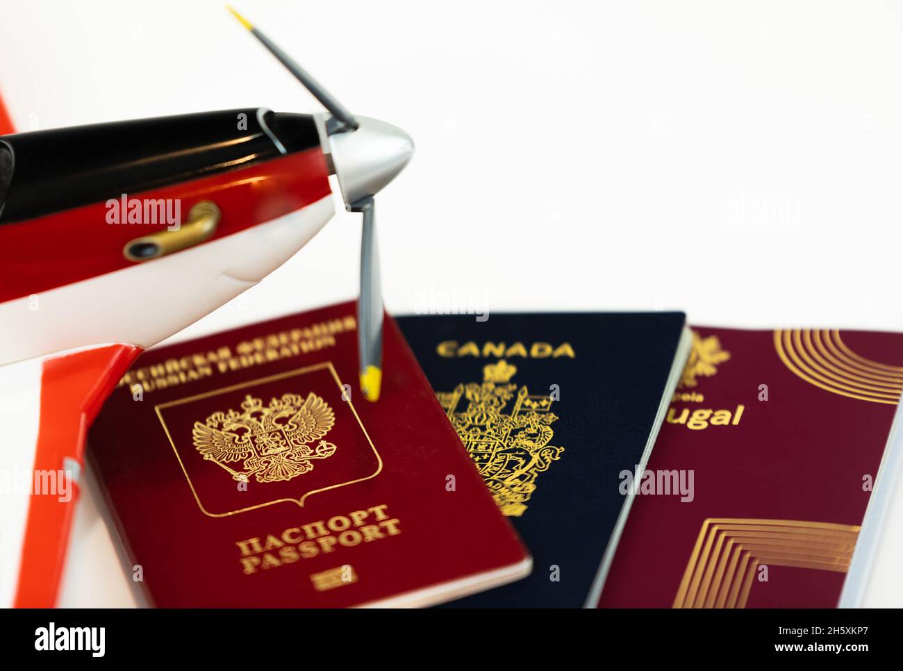 Tre diversi passaporti isolati su bianco. Passaporti canadesi, portoghesi e russi per l'ingresso in diversi paesi. Primo piano, sfocato, selettivo Foto Stock