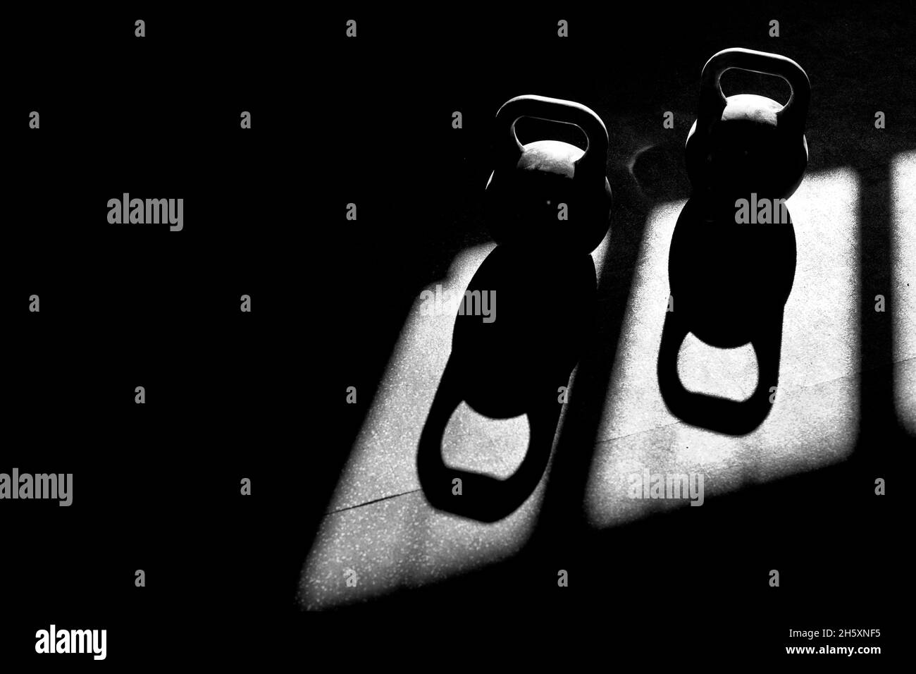 kettlebells sul pavimento in una palestra con una luce drammatica Foto Stock