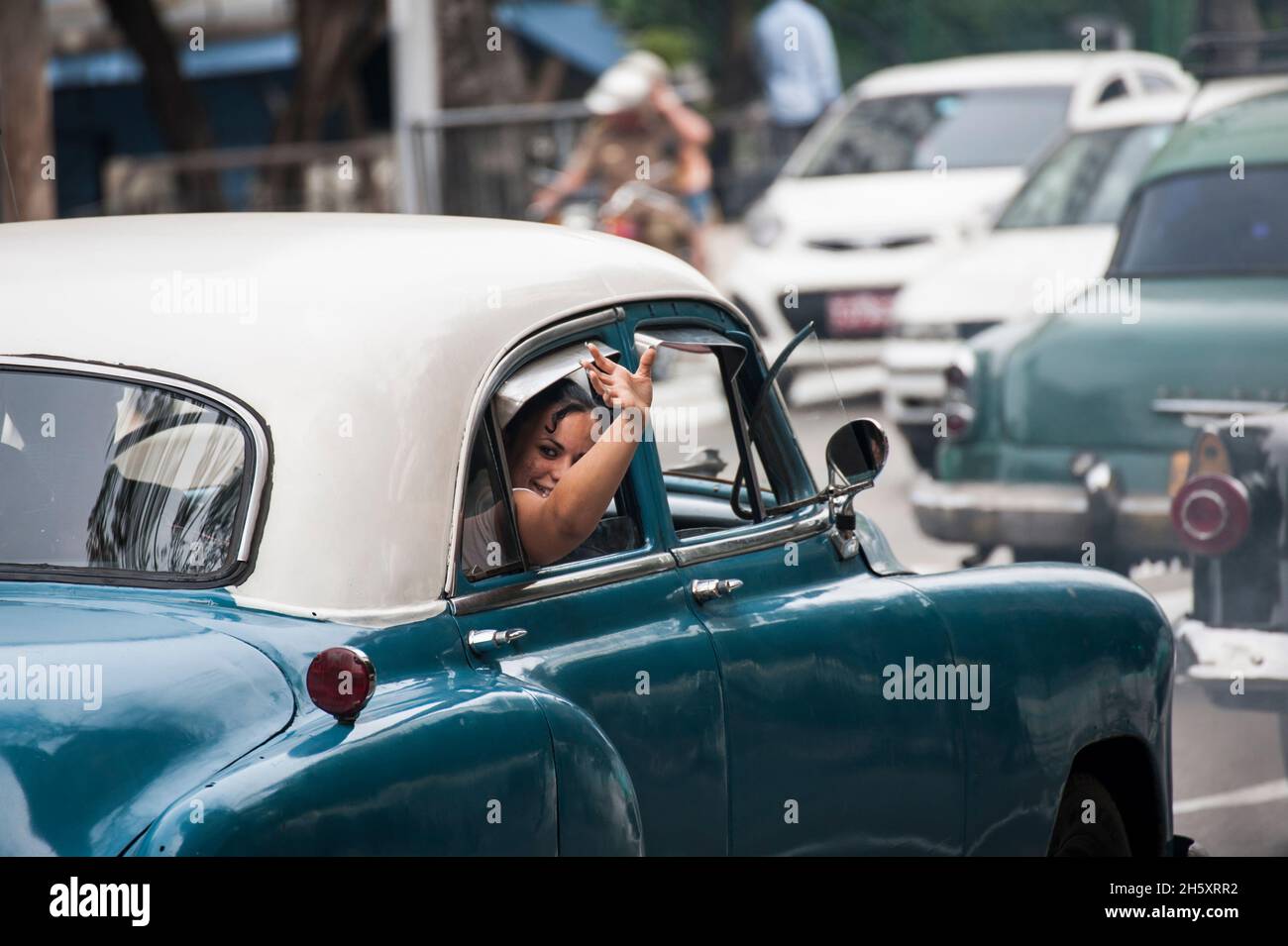 Donna che sventola ad un amico da una vettura classica a l'Avana, Cuba. Foto Stock