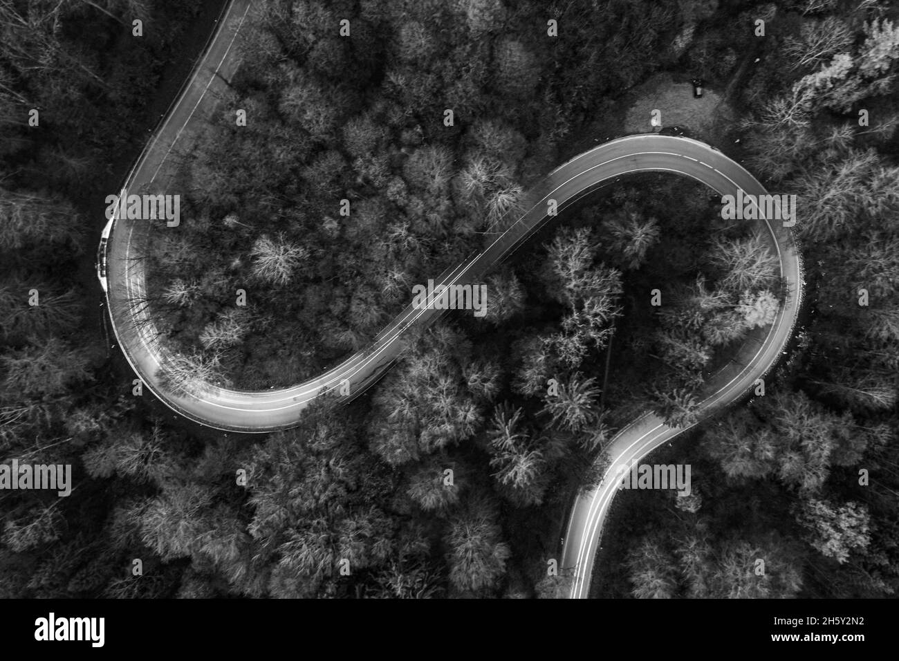 Strada curvilinea dall'alto con percorsi leggeri di auto in bianco e nero. Foto Stock