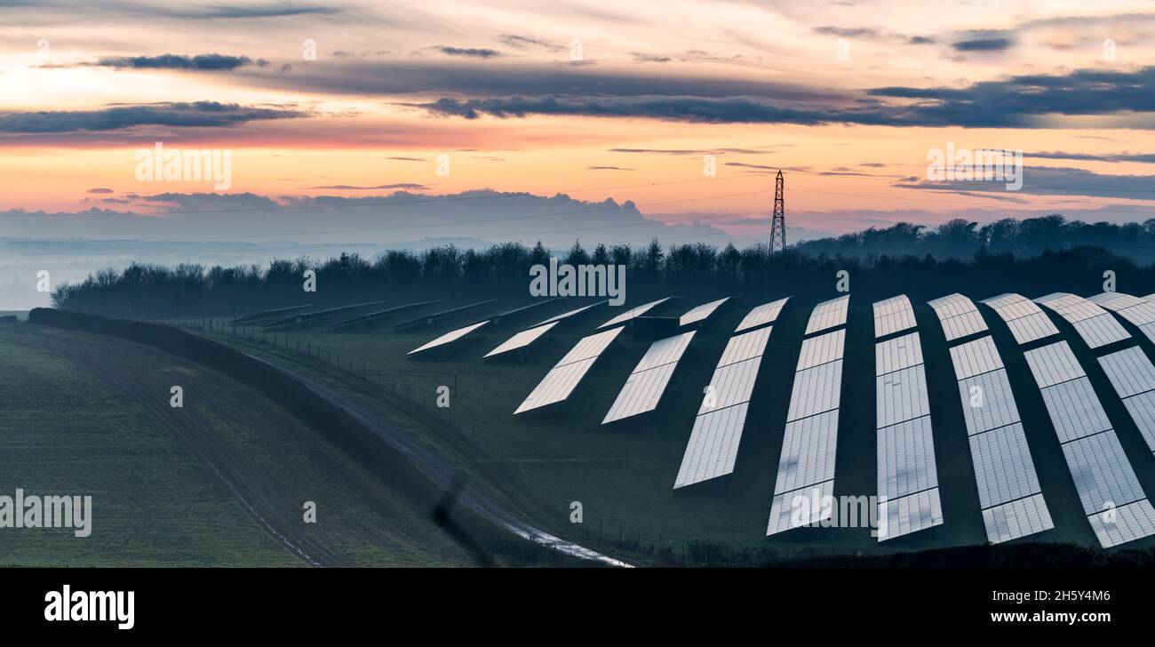 Scena del crepuscolo, file di pannelli solari che sono stati alimentati dal sole d'inverno, come nebbia appende sulla campagna dopo il tramonto in una giornata limpida nel sud di Engla Foto Stock