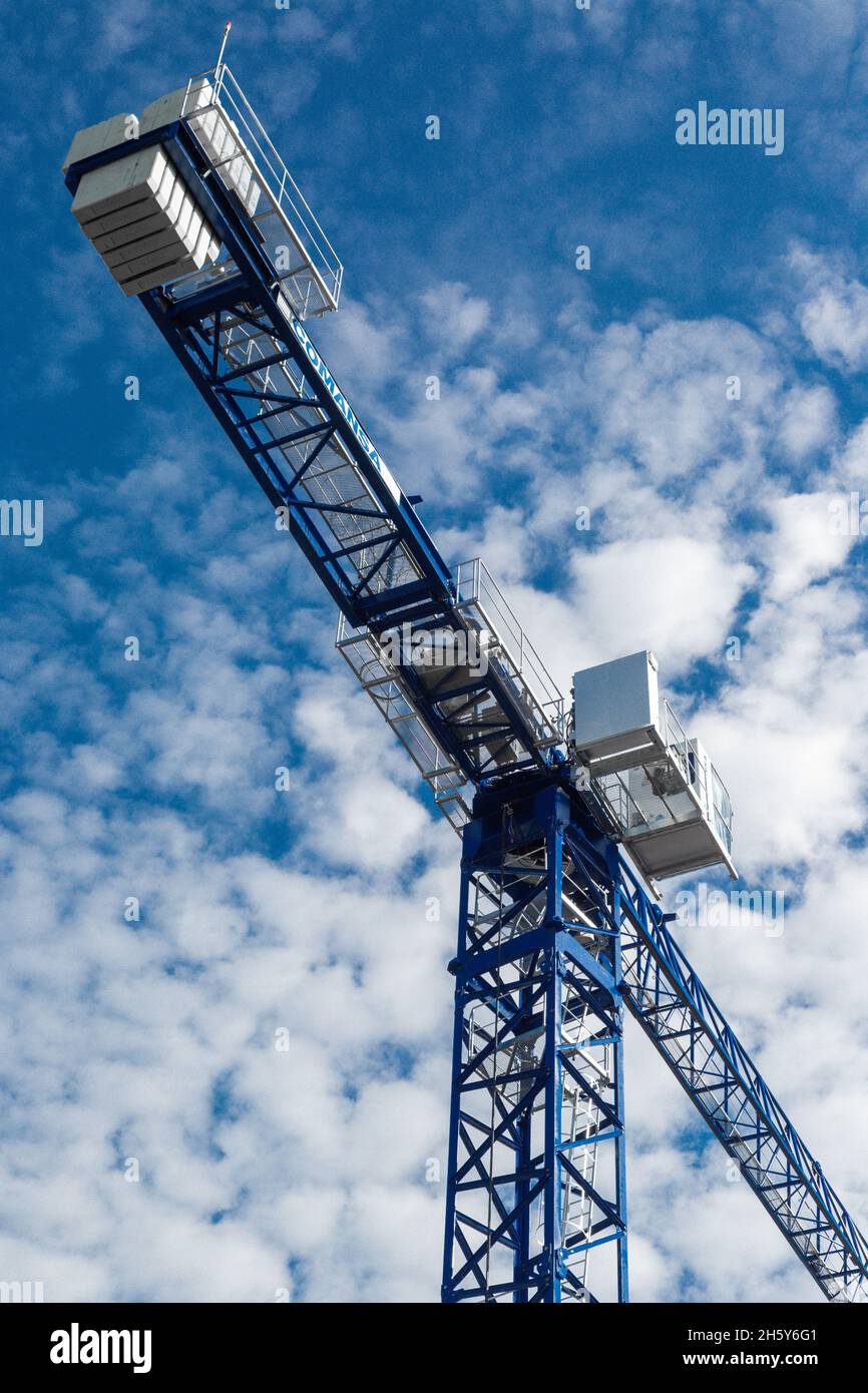 Torreggiante gru blu contro un bel cielo blu con nuvole. Foto verticale, vista dal basso. Foto Stock