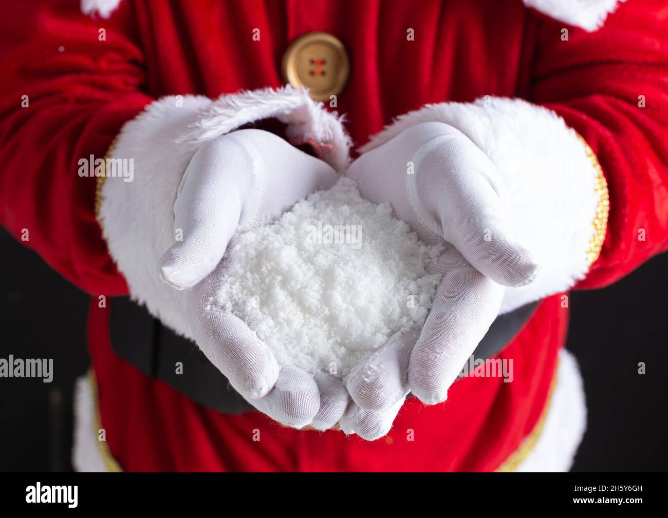 Le mani di Babbo Natale tenendosi in mano una manciata di fiocchi di neve. Foto Stock