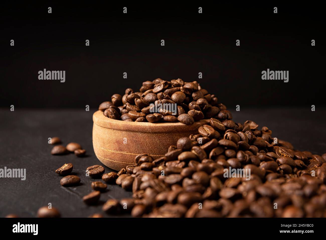 Chicchi di caffè tostati organici su un rustico tavolo in pietra nera con spazio per copiare il testo su sfondo nero Foto Stock