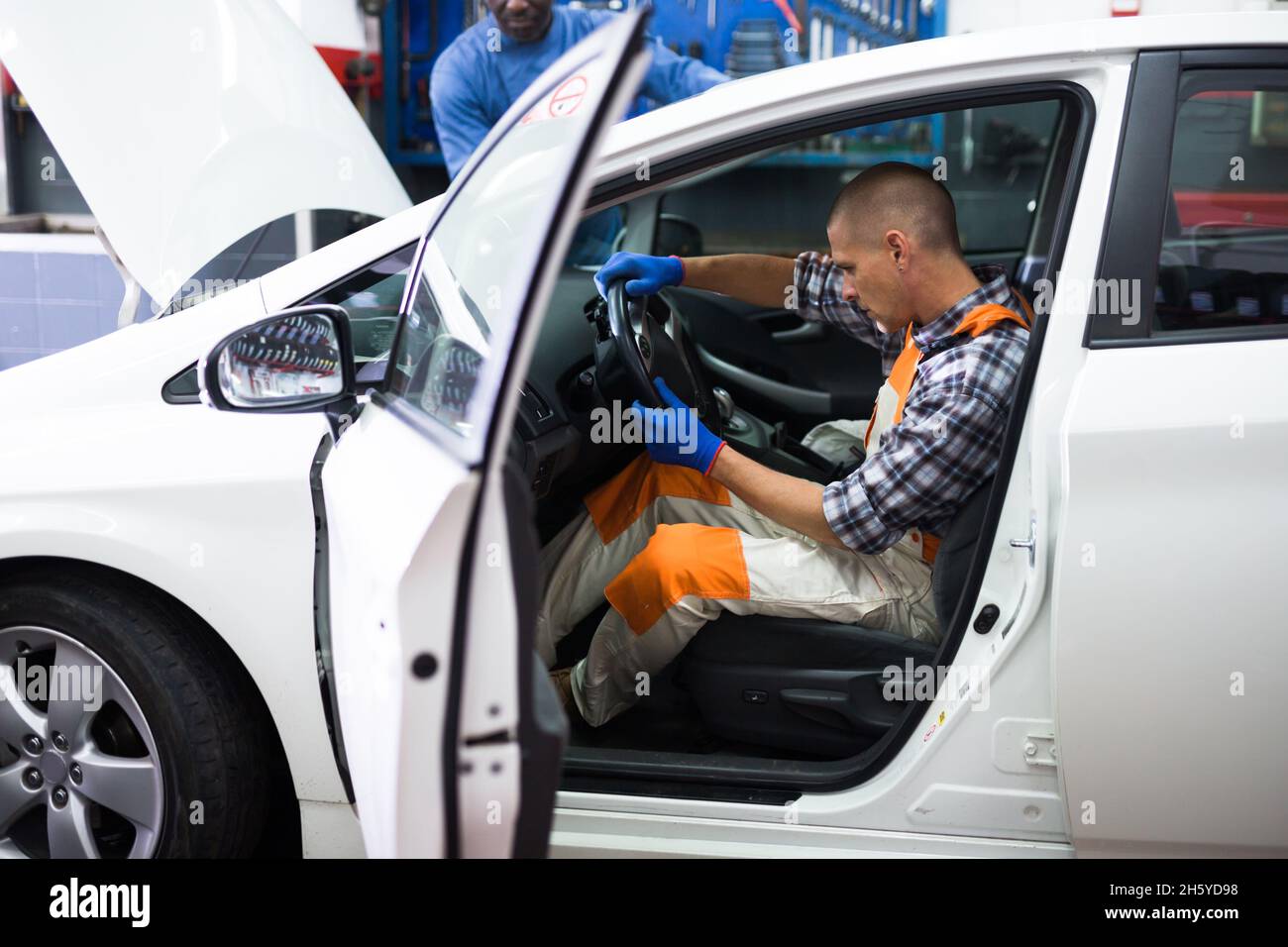 Addetto all'assistenza che effettua la diagnostica dell'auto in officina Foto Stock