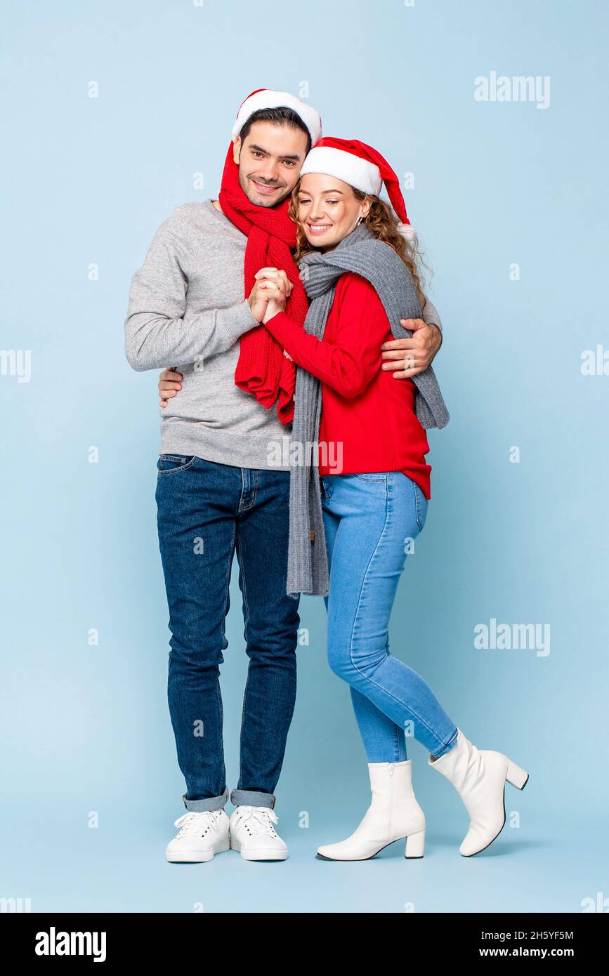 Ritratto a tutta lunghezza di felice coppia caucasica in abiti di Natale che si tengono in luce blu isolato sfondo studio Foto Stock
