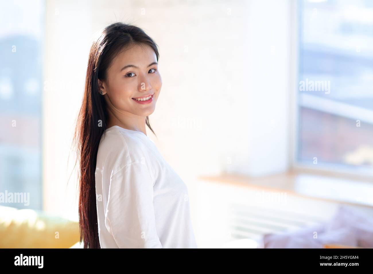 Ritratto di donna asiatica sorridente sullo sfondo interno dell'appartamento. Foto Stock