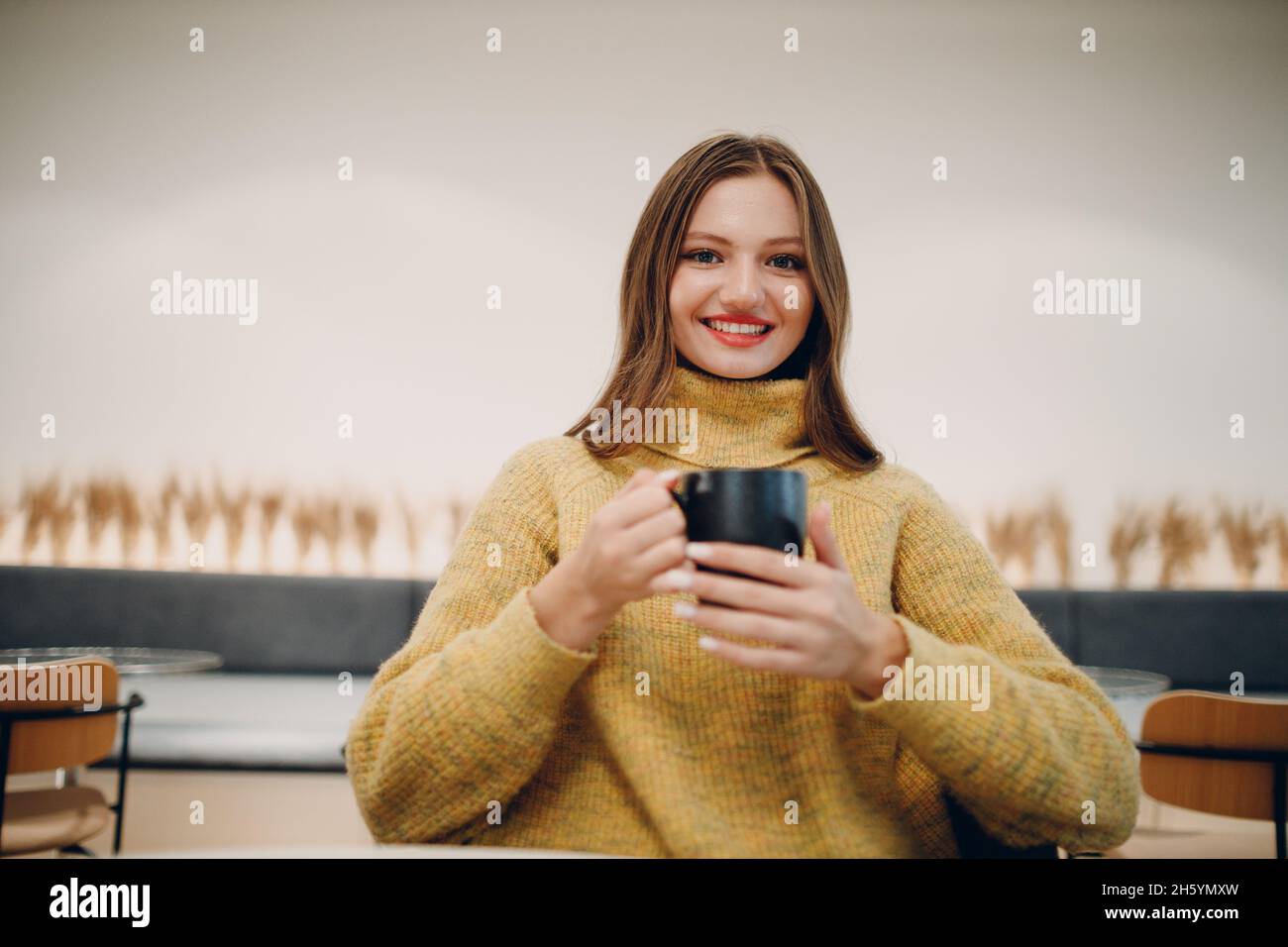 Giovane donna di 20 anni che beve caffè al mattino al caffè. Foto Stock