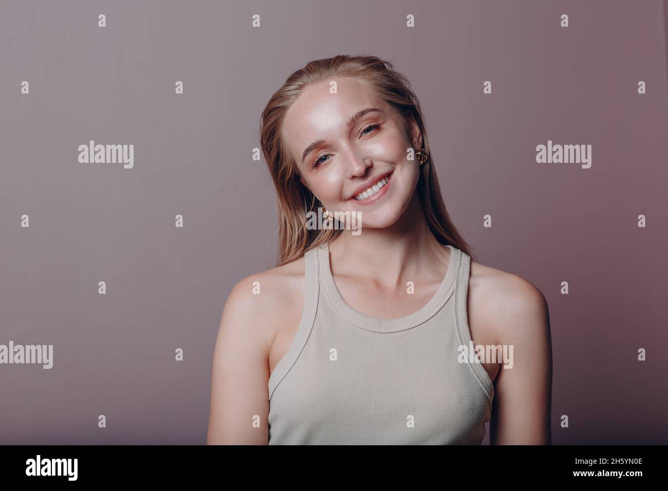 Ritratto di giovane 20-25s anni sorridente donna europea. Bella ragazza bionda felice indossa la t-shirt e guarda la macchina fotografica. Studio sparare isolato su sfondo rosa. Foto Stock