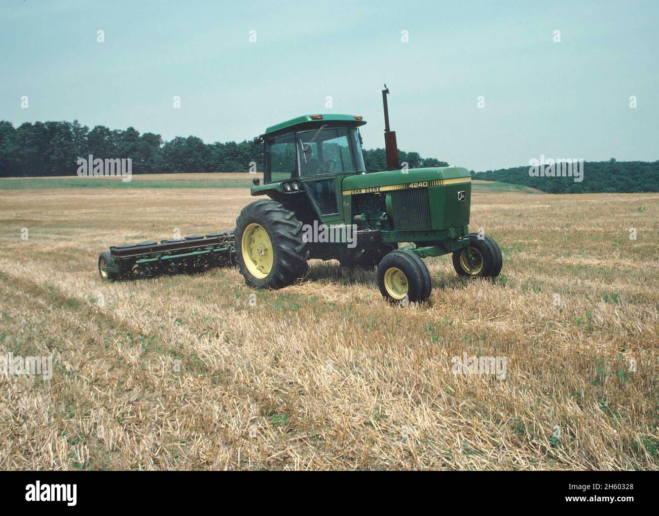 Agricoltore che guida il trattore John Deere 4240 nel suo campo. Questi trattori sono stati fabbricati a partire dal 1979-1982 Foto Stock