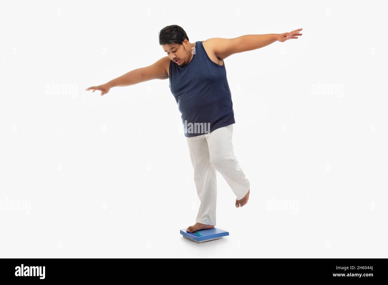 Ritratto di un uomo grasso in piedi una gamba con le braccia allungate sulla macchina di pesatura. Foto Stock