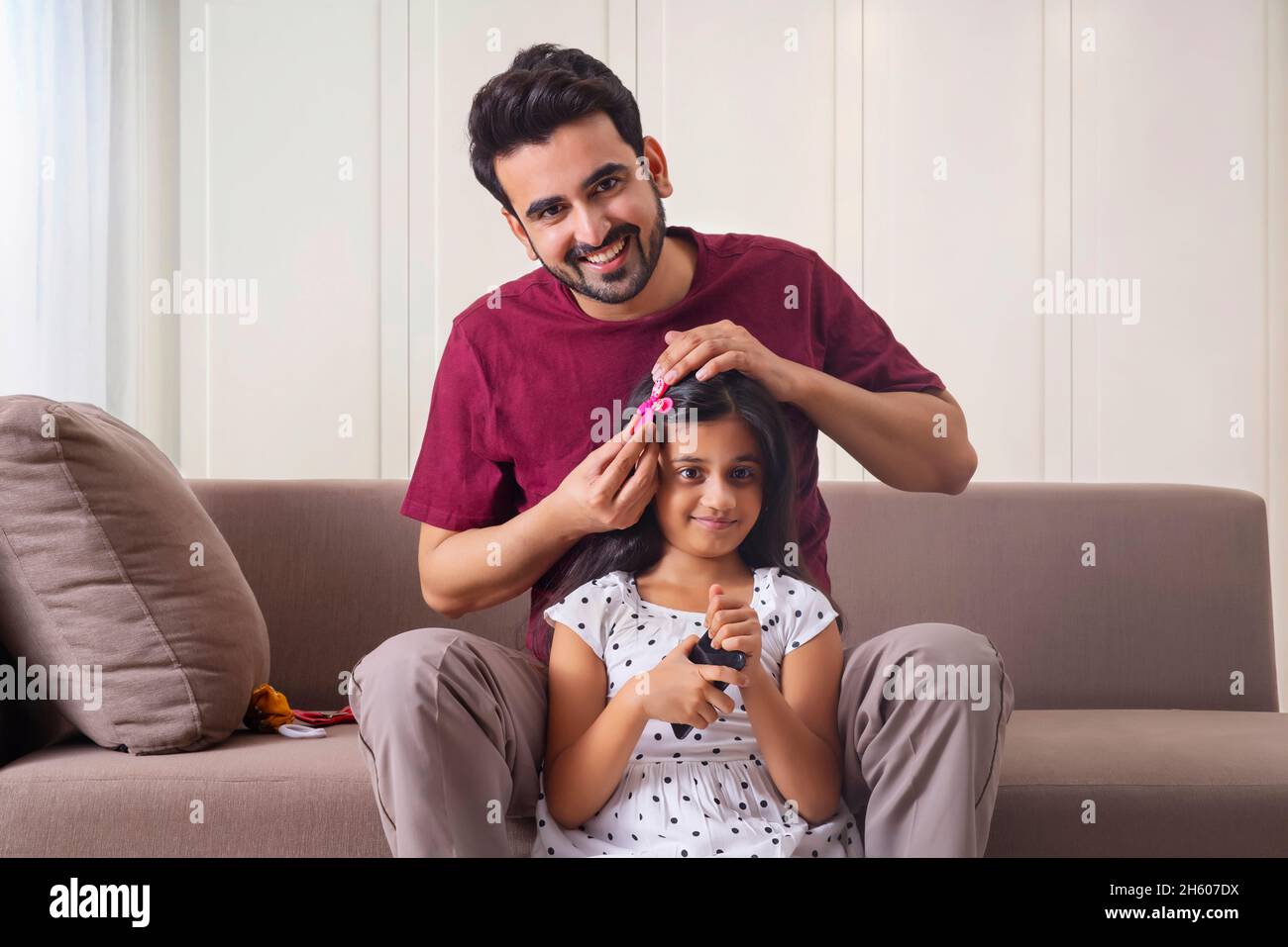 UN PADRE CHE GUARDA LA FOTOCAMERA MENTRE GROOMING FIGLIA Foto Stock