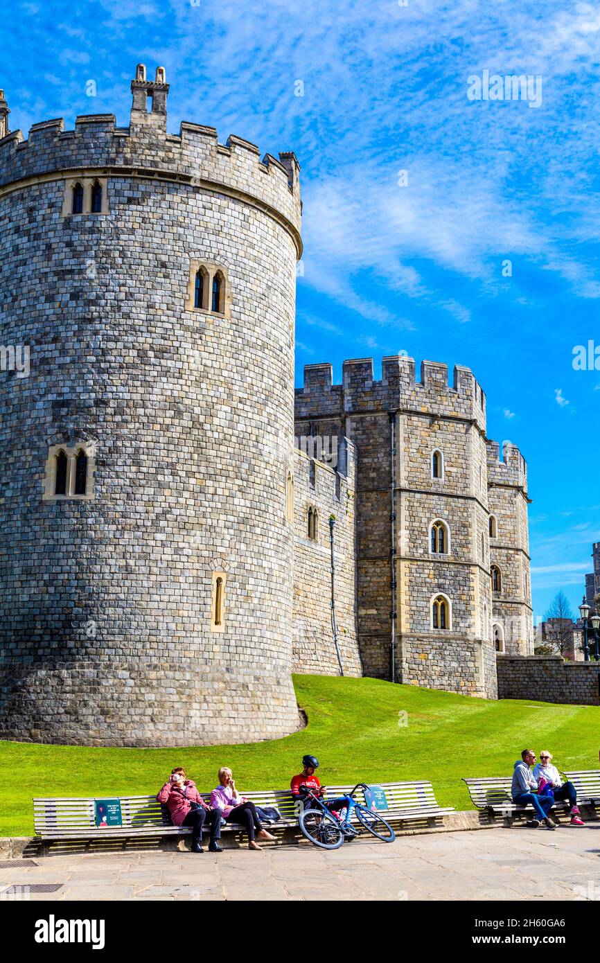 Turisti seduti su panchine e all'esterno della residenza reale medievale 11 ° secolo Windsor Castle, Windsor, Berkshire, Regno Unito Foto Stock