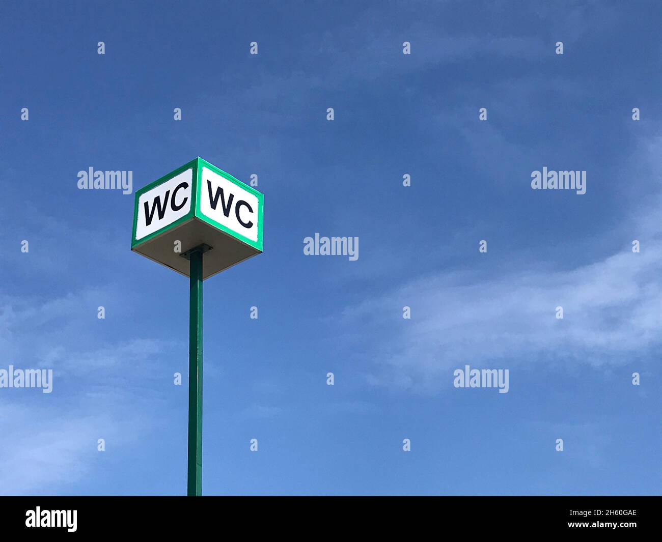 WC logo, segno di servizi igienici pubblici sulla strada su sfondo cielo. Foto Stock