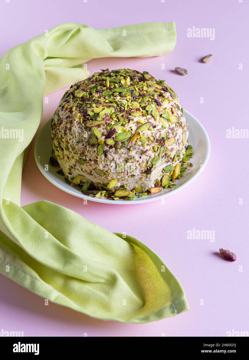 Halva al sesamo con pistacchi, poche noci sparse e tovagliolo di lino verde su carta rosa. Vista ad angolo alto. Dolci tradizionali mediorientali. Ebraico, tu Foto Stock