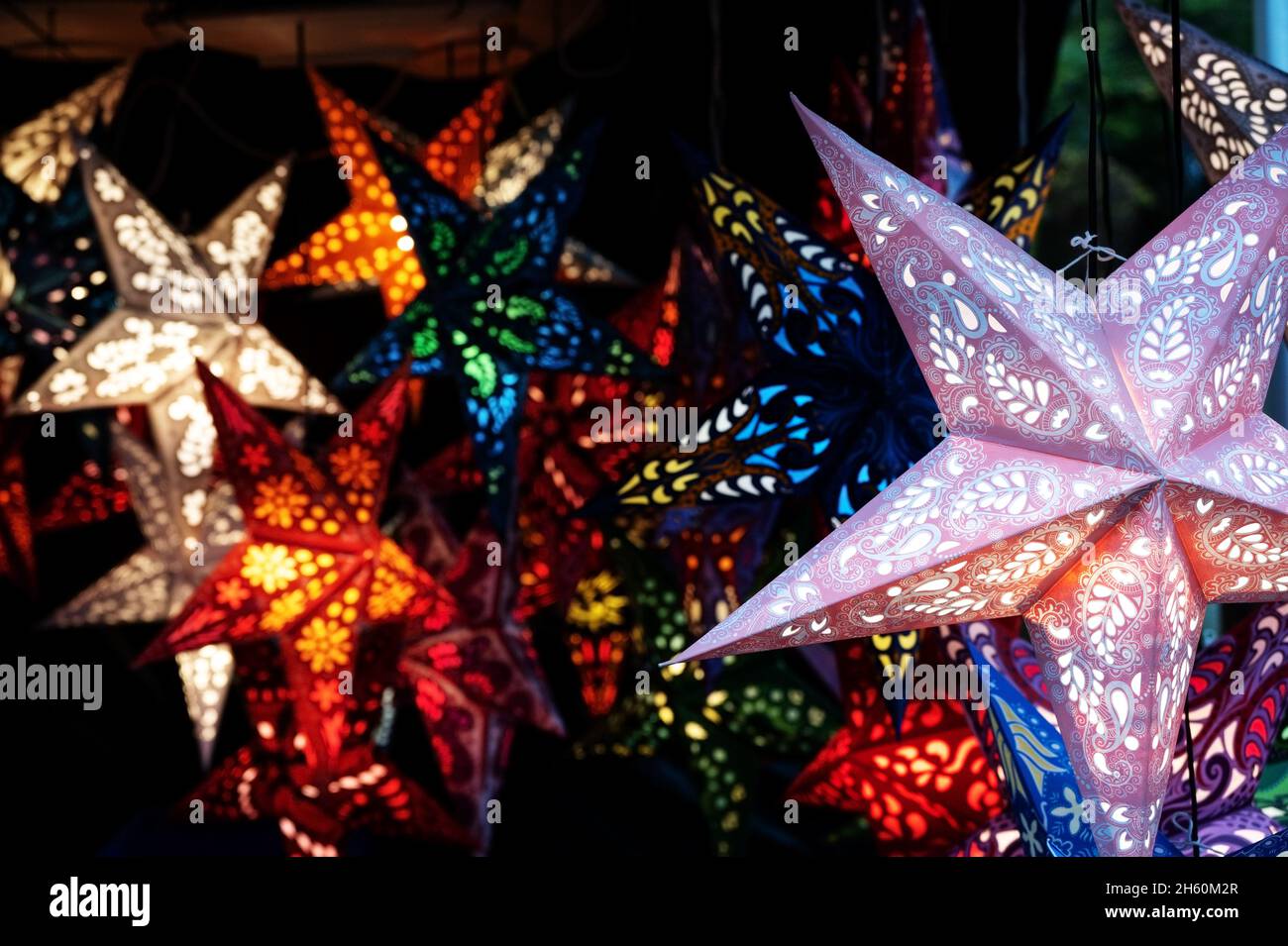 Lanterne di Natale in forma di stella da carta piegata in uno stand di mercato di notte, vendere luce per le vacanze invernali buie, spazio copia, selecte Foto Stock Lanterne di Natale in forma di stella da carta piegata in uno stand di mercato di notte, vendere luce per le vacanze invernali buie, spazio copia, selecte Foto Stock