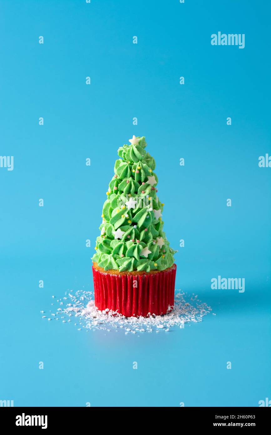Nevicando sui cupcakes dell'albero di Natale isolato su sfondo blu Foto Stock