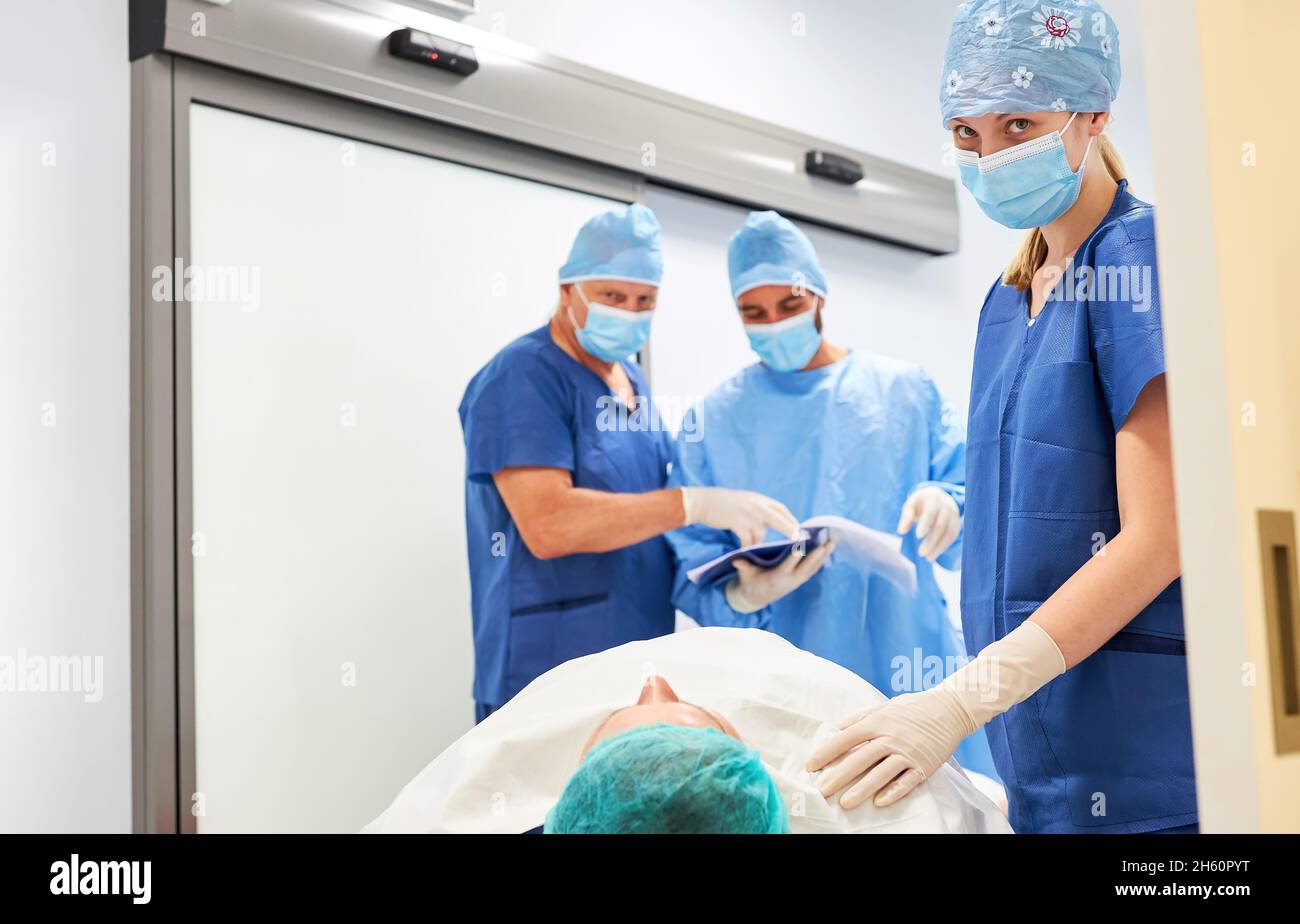 Chirurghi con cartelle cliniche durante la pianificazione chirurgica con infermiere e paziente in primo piano Foto Stock