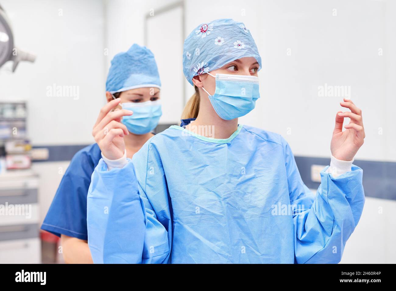 Nurse aiuta il medico a mettere su abito in chirurgia prima di chirurgia Foto Stock