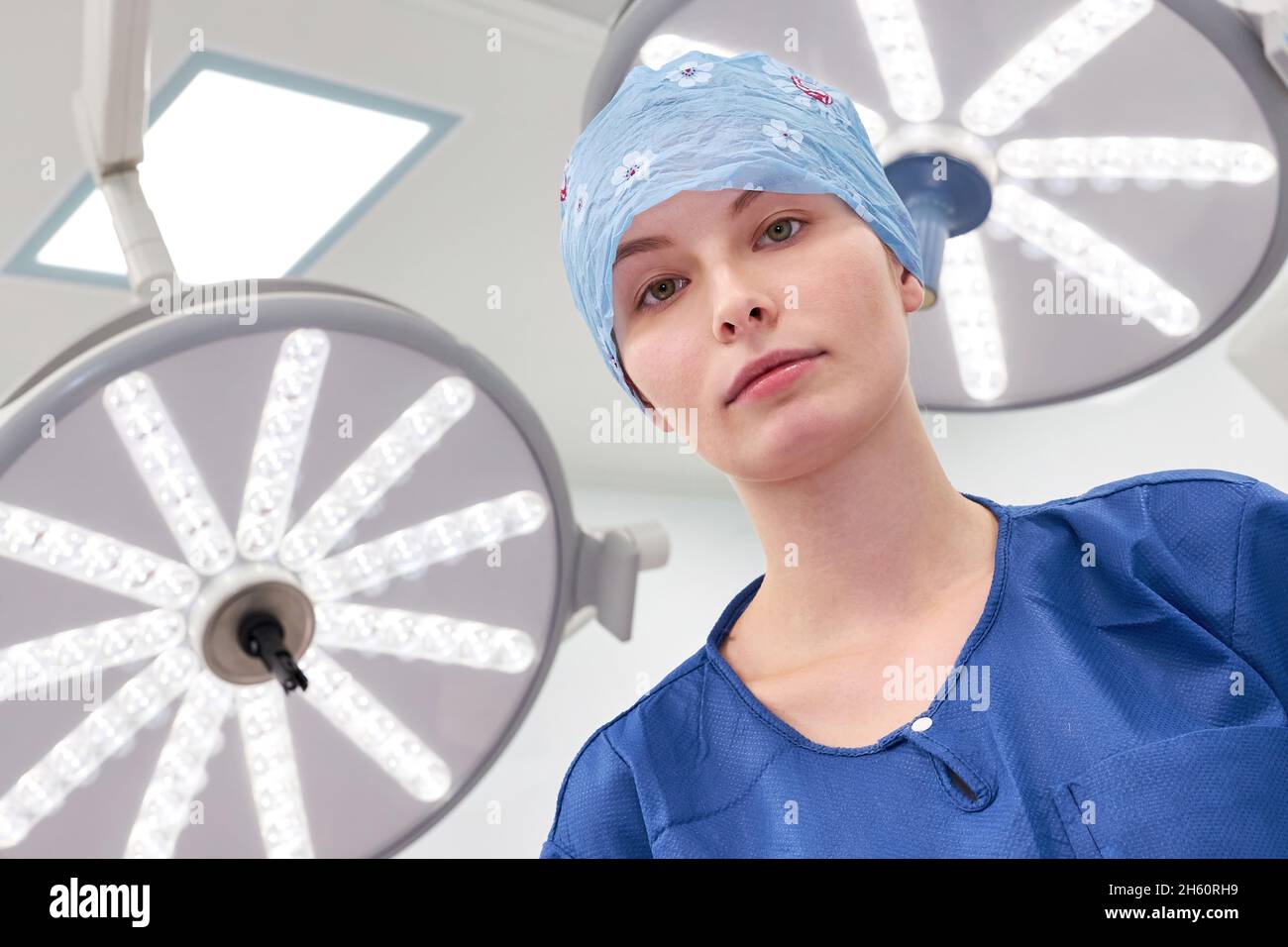 Giovane donna come medico in tirocinio o operatorio infermiera con cappuccio nella sala operatoria della clinica Foto Stock