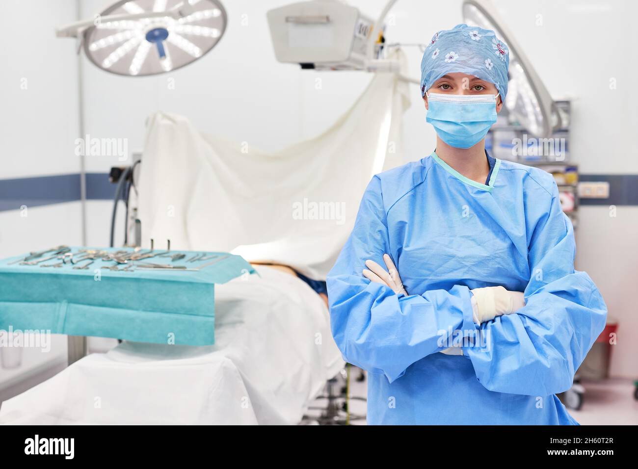Giovane donna in abbigliamento protettivo come medico o infermiere della sala operatoria con braccia incrociate nella sala operatoria Foto Stock