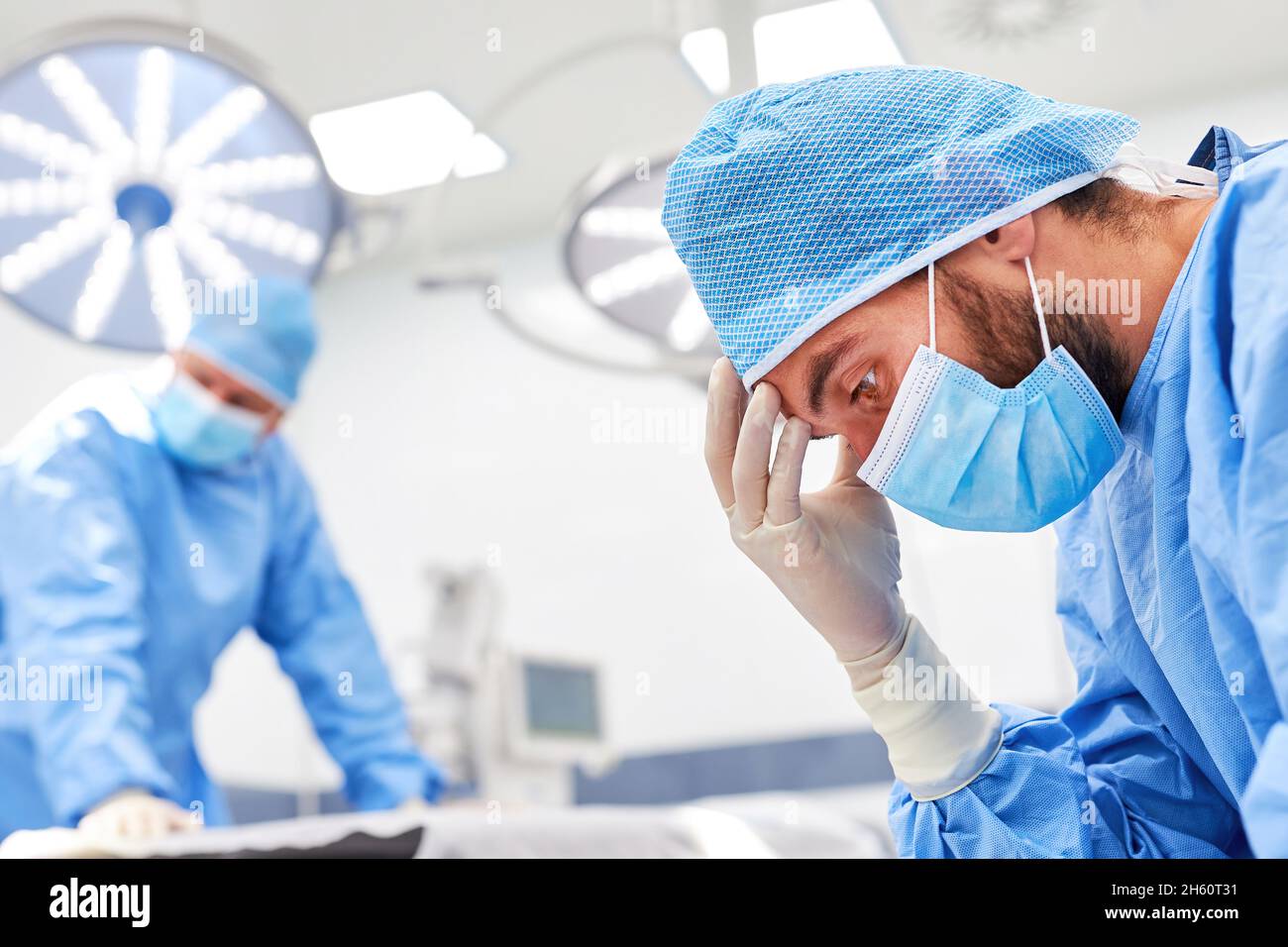 Due chirurghi esausti dopo un'operazione faticosa per lavori in eccesso e burnout Foto Stock