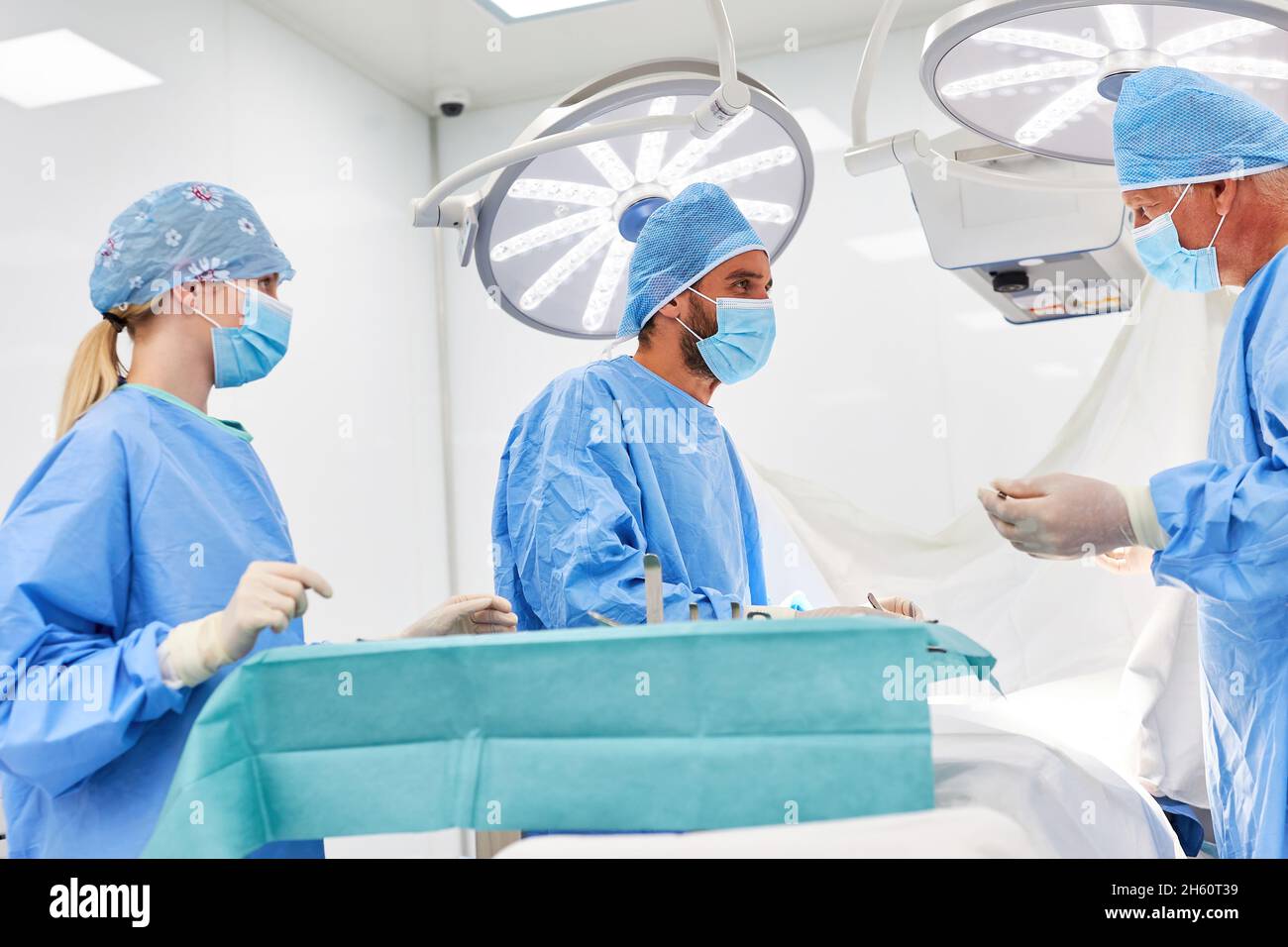 Il medico senior e il medico assistente lavorano insieme in un'operazione di emergenza nella sala operatoria Foto Stock