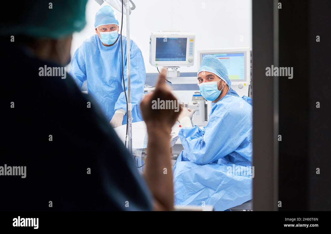 Medici in un reparto di isolamento dietro il vetro in un ospedale durante una pausa Foto Stock