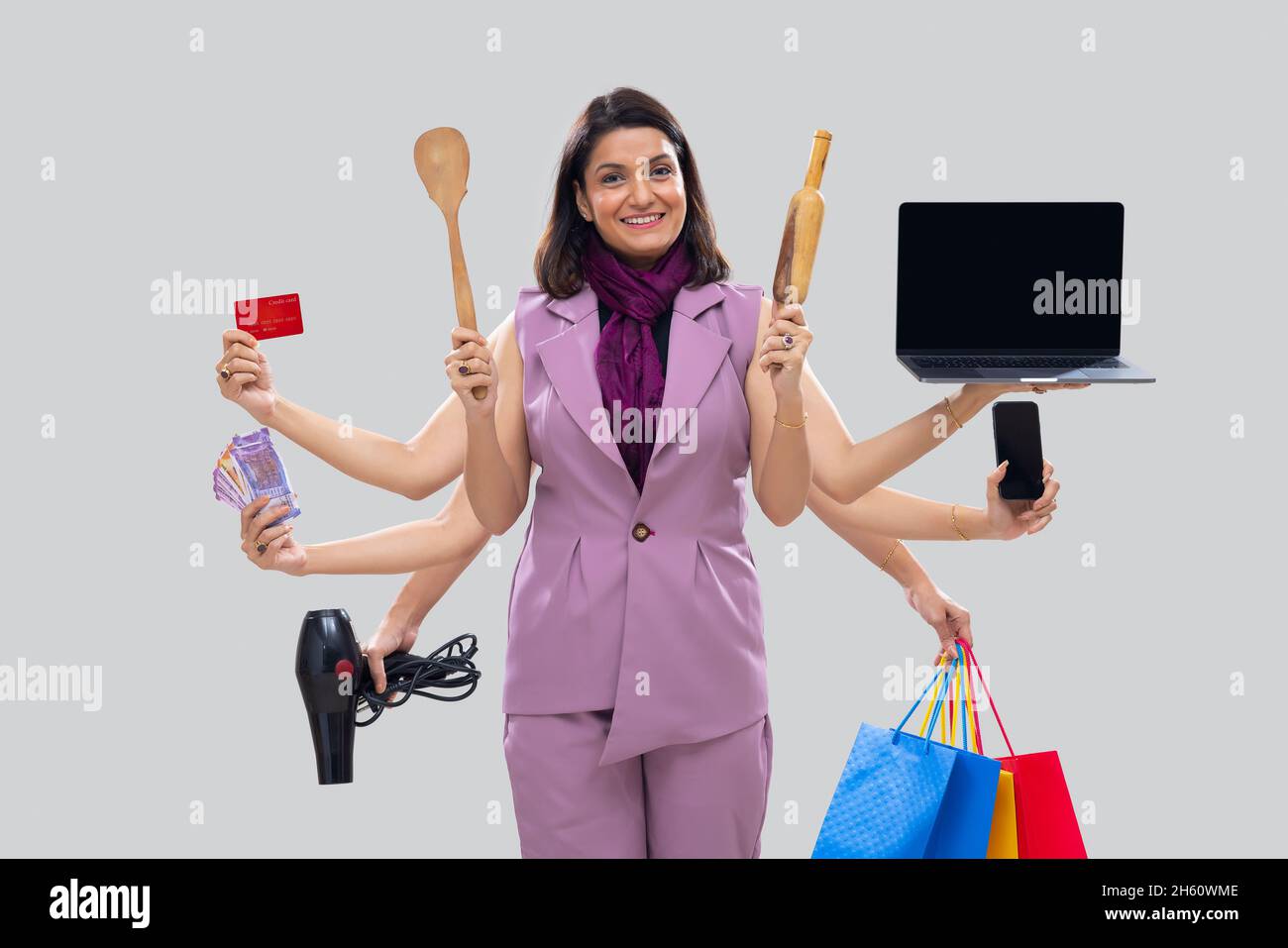 Ritratto di una casalinga donna multitasking con mani multiple che reggono vari oggetti Foto Stock