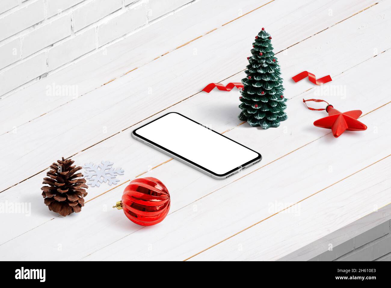 Telefono di Natale mockup in posizione isometrica. Composizione su banco di legno bianco. Display telefono isolato per la promozione del design delle app Foto Stock