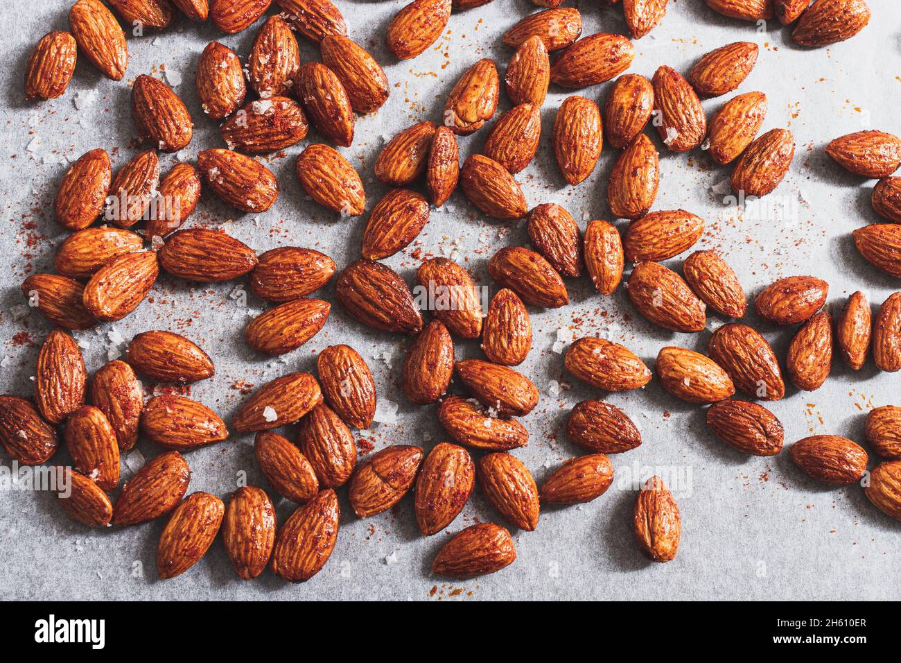 Mandorle crude preparate con olio d'oliva, sale marino e paprika affumicata su una teglia da forno pronta per essere tostata. Foto Stock