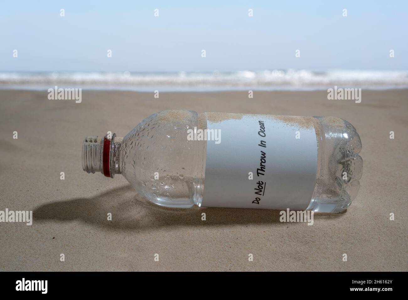 Una bottiglia di plastica scartata con il messaggio "non gettare nell'oceano". Foto Stock