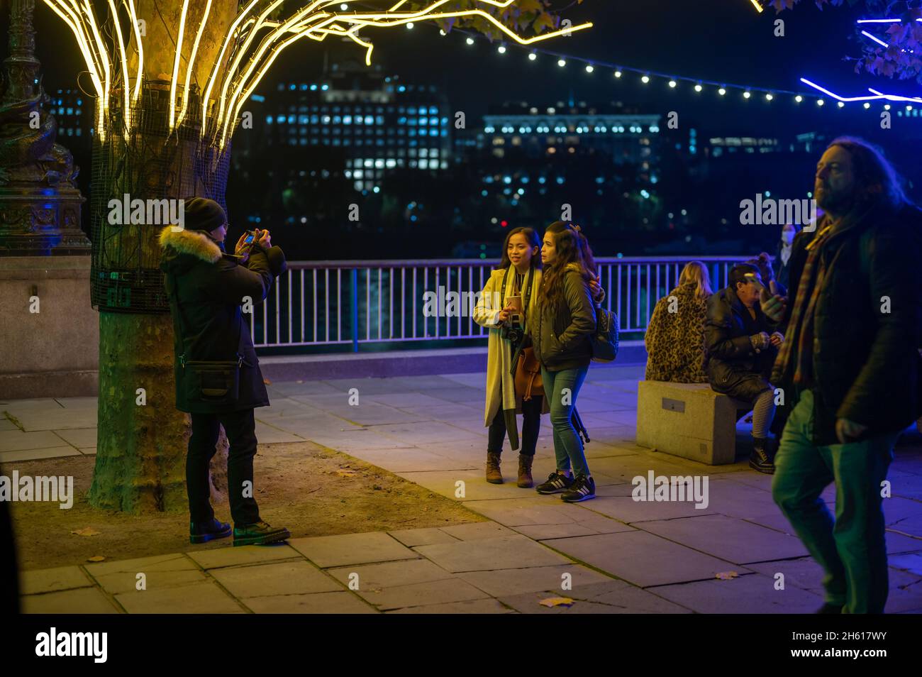LONDRA - 1 NOVEMBRE 2021: Gli acquirenti posano per una fotografia sotto le decorazioni natalizie di Southbank di notte Foto Stock
